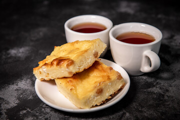 Two cups with tea, cottage cheese casserole on a saucer. Breakfast. Close-up. Selective focus.