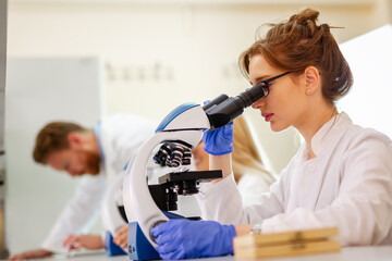 Scientist using a microscope in a laboratory, Testing for coronavirus covid19 vaccine