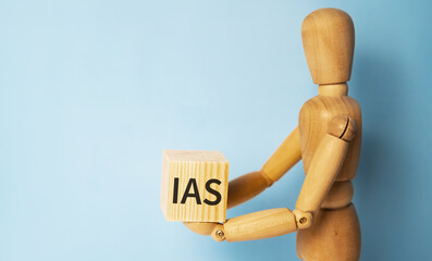 Wooden man holding a wooden cube with acronym IAS-International accounting standards. Business and finances concept.