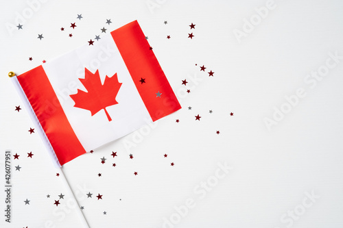 Happy Canada Day greeting card poster with Canadian flag and confetti on white background. Flat lay, top view.