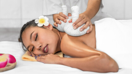 Obraz na płótnie Canvas woman has Thai massage therapy with Thai herbal hot compress ball