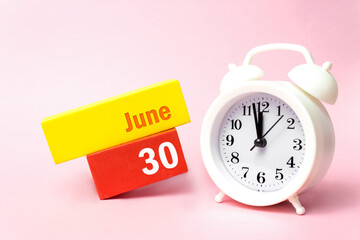 June 30th. Day 30 of month, Calendar date.White alarm clock on pastel pink background. Summer month, day of the year concept.