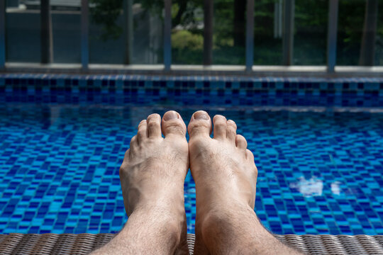 Close up of man's bare feet against swimming pool on a sunny day - Powered by Adobe
