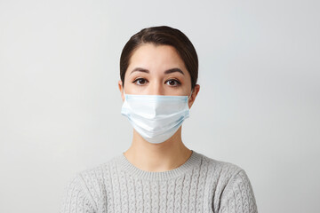 Young woman wearing medical mask, white background.