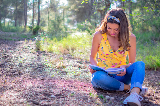 Joven mujer leyendo un libro en la naturaleza. Disfrutando de la lectura. Concepto de libro. 