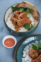 Turquoise bowl with indian butter chicken or Murgh Makhani, vertical shot on a grey concrete background, selective focus