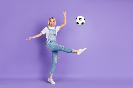 Full size profile side photo of young girl happy positive smile play kick soccer ball game match isolated over purple color background