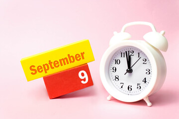 September 9th. Day 9 of month, Calendar date.White alarm clock on pastel pink background. Autumn...