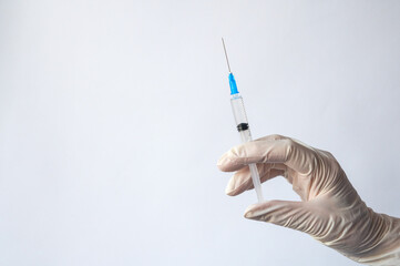 women's hands in white rubber medical gloves hold a syringe with medicine on a white background. The concept of health and vaccination, place for text