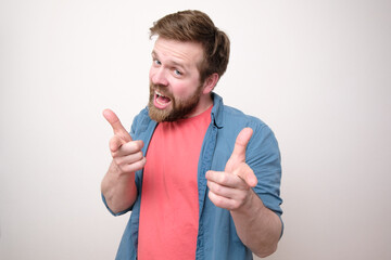 Persuasive Caucasian man points his index fingers at someone and looks approvingly. White background.