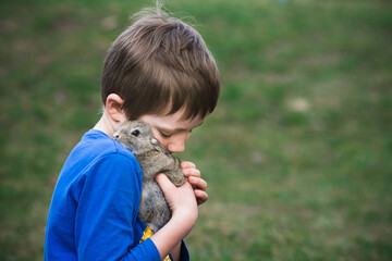 caucasian boy with his furry friend little rabbit. Kid and animal care concept with copy space.
