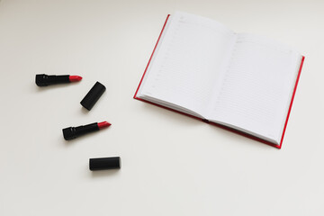 open notebook with cosmetics, accessories on white background. Minimal home workspace desk table. Flat lay, top view, mockup with copy space