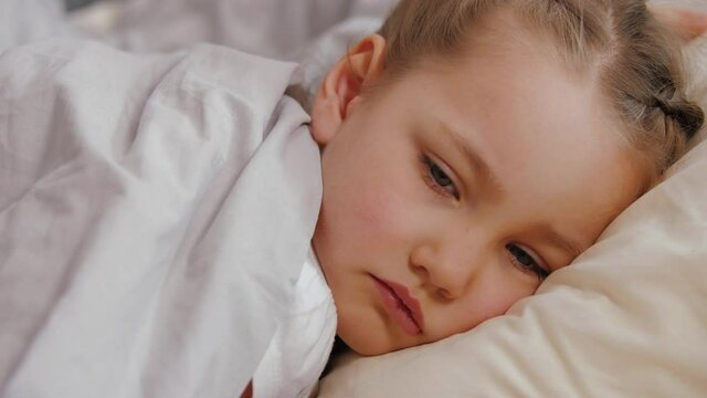 Portrait of sick little girl lying on bad, cold flu virus disease concept