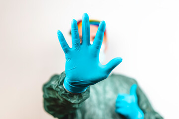 Surgeon doctor with protective mask and rainbow bandanna on his head who is showing his hand in blue glove - Doctor stopping hiv virus or coronavirus with prevention - Lgbtq people rights concept