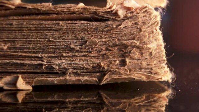 Time and knowledge concept, An eye glass specs kept in front of a really old torn and partially damaged religious scripture book. Extreme macro close up shot of an old vintage book