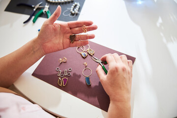 Handcrafter with a pair of pliers and jewelry items