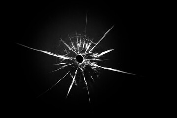 Cracked texture on a black background. Broken glass bullet from a shot