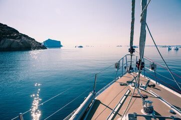 Yacht sailing among icebergs in Atlantic ocean in Greenland. Summer seascape