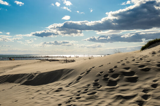 South of France beach at sunset with cloudy sky in the background, and sand dunes in the foreground, shot near Agde, Herault, France