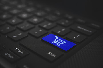 Online shoping concept. Shoping cart on blue laptop keyboard