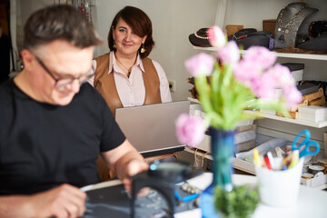 Smiling mature lady looking at a busy male jeweler