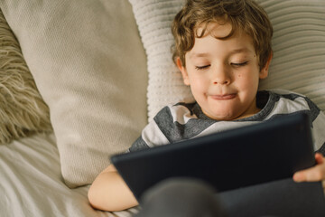 Little Boy with a tablet in the room. The boy play game on the tablet. Technology concept.