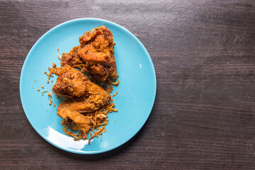 Top view Fried chicken and fried onion in the light blue dish on brown wooden. fried chicken the most famous food of Hat-yai Songkhla Thailand. Culture food. Fat food.