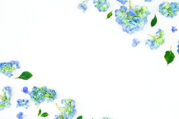 Floral frame of blue flowers and leaves on white background. Flat lay