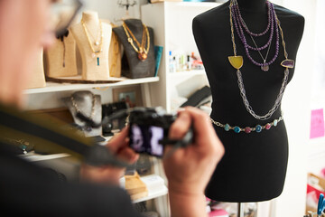 Jeweler photographing his handcrafted necklaces on the female mannequin