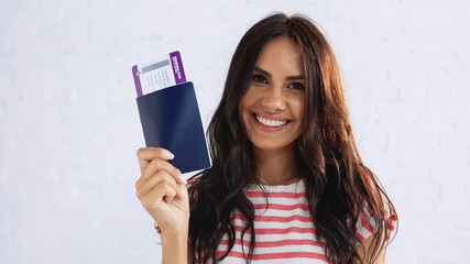 happy woman holding passport with air ticket and looking at camera