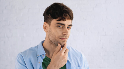 pensive man touching chin while looking at camera