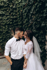 Walk of the bride and groom in the summer park. Newlyweds in seclusion. He and she against the backdrop of green foliage.