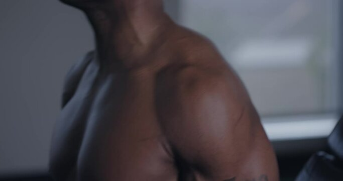 Closeup, Muscular arms and pecs of black man lifting weights, tilt up to face