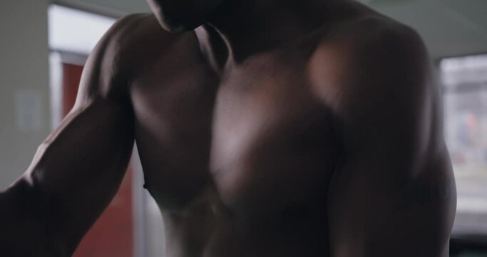 Shirtless black man exercising with battle ropes in intense workout, Closeup