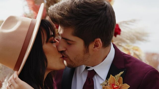 Man in Burgundy Tuxedo Kisses Beautiful Woman in Fedora Hat, Slowmo Closeup