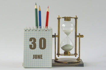 Day of month.Calendar,sand in vintage hourglass, colored pencils, notepad,procrastination and...