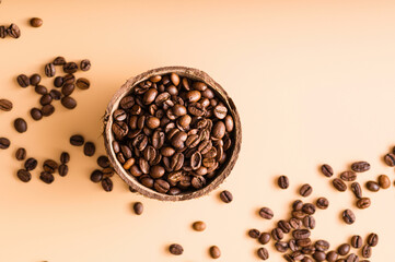 black arabica coffee beans, aromatic in a coconut dish, sprinkled beans on the table, light background, close-up, top view