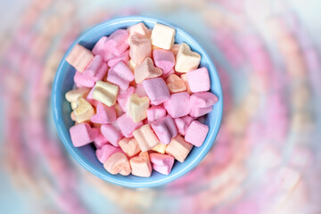 Colored marshmallow like hearts in a ceramic bowls from a top view