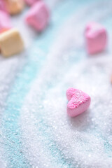 Colored marshmallow like hearts on light-blue background covered with sugar