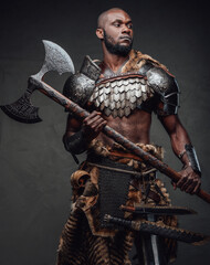 Wild african soldier wielding an axe and posing in dark background