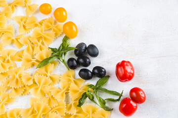 Pasta ingredients, raw pasta, cherry tomatoes, olives and basil leaves