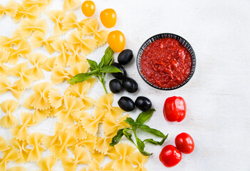 Pasta ingredients, raw pasta, cherry tomatoes, olives and basil leaves