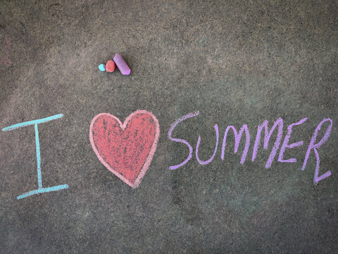 The inscription text on the grey board, I with hand drawn love symbol and summer . (I love summer). Using color chalk pieces.