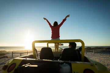 Happy caucasian couple on beach during sunset woman sitting on beach buggy man sitting in