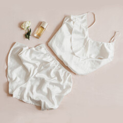 Women silk lingerie, perfume and a rose on beige background, flatlay, top view. Female elegant lace...
