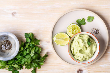 Avocado hummus dip on rustic wooden table, top view