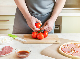 hands chefs cut tomatoes, cooking pizza ingredients on wooden board