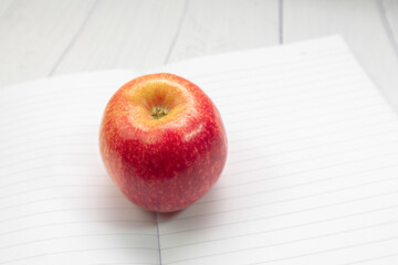 Red apple on the notebook with open. Copy space for text. Selective focus. Knowledge concept. education  concept.