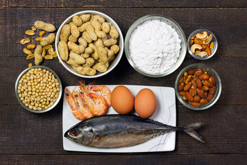 Major food allergens include egg, penuts, fish, shrimp, wheat flour, soya, almond and cashew nut on rustic wooden table, top view. Allergy food concept.