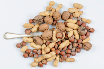 Silver spoon with mixture of nuts on white background. Concept of proper food.